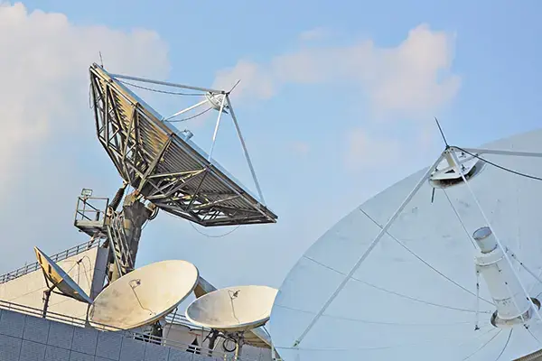 Array of large satellite parabolic dish antennas pointed toward the sky at a telecommunications ground station.